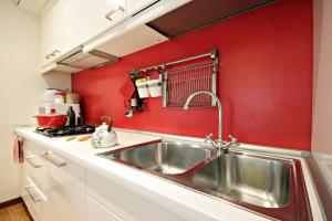cocina con fregadero y pared roja en Apartment A Casa di Papà, en Roma
