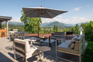 eine Terrasse mit Tischen und Stühlen und einem Sonnenschirm in der Unterkunft LA Villa Du Lac in Annecy
