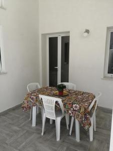 een eettafel met witte stoelen en een tafelkleed bij Santa Genoveffa Apartment in Trapani