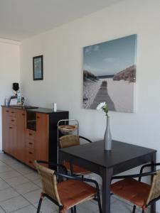 a dining room with a table and chairs and a picture on the wall at Appartement La Corniche Vue océan in Mimizan-Plage