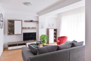 uma sala de estar com um sofá cinzento e uma cadeira vermelha em Apartments Danijela & Love Nest em Rijeka