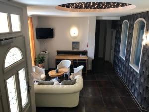 Una sala de estar con un sofá y sillas y una mesa. en Les Pastels, en La Roche-sur-Yon