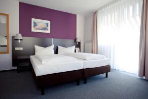a bedroom with a large bed with a purple wall at Akzent Hotel Torgauer Hof in Sindelfingen