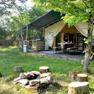 una tienda con una mesa y algunos troncos en el césped en La lodge du Refuge, en Valigny