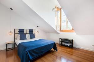 a bedroom with a bed with a blue blanket and two windows at Stunning and Spacious Lofts just by Graça and Alfama in Lisbon