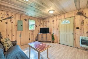 een woonkamer met een bank, een tafel en een tv bij Rustic Cabin on Farm about 4 Mi to Kentucky Lake! in New Concord