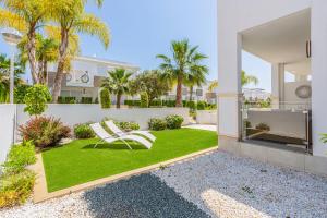 a garden with two white chairs on a lawn at Esquina Soleada in Ciudad Quesada