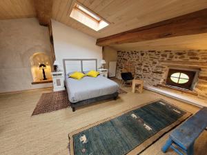 ein Schlafzimmer mit einem Bett und einer Steinmauer in der Unterkunft La Cressonnière in Parthenay