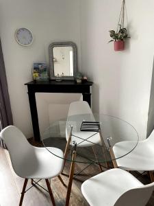 a glass table with three white chairs and a mirror at Appartement Rue de la gare centre ville in Quiberon