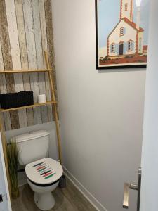 a bathroom with a toilet and a picture of a house at Appartement Rue de la gare centre ville in Quiberon +2 photos
