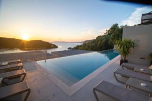 a swimming pool with a view of the ocean at sunset at Sivota Deamaris Luxury Boutique Hotel in Syvota