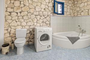 a bathroom with a toilet and a washing machine next to a tub at Stone House in olive Grove - former Denis Stone Villa in Trapezaki +57 photos