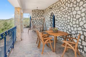 a patio with a wooden table and chairs on a balcony at Stone House in olive Grove - former Denis Stone Villa in Trapezaki
