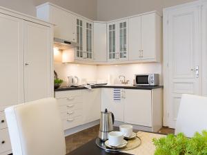 a kitchen with white cabinets and a table with cups at Antique Apartments Old Town in Kraków