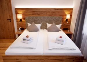 un dormitorio con una cama con sábanas y almohadas blancas en DEVA Hotel Alpenglück, en Weißbach