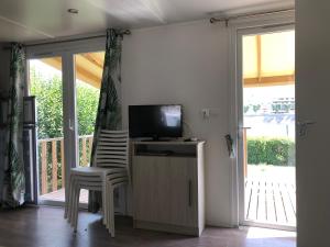 a room with a tv and a chair and a sliding glass door at Camping le Rhône in Tournon-sur-Rhône