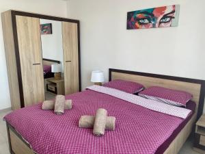 a bedroom with a bed with purple sheets and pillows at Elite Apartment in Târgovişte