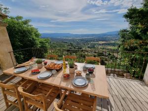 a wooden table with food on top of a balcony at Maison au centre du village de Gordes avec vue incroyable in Gordes