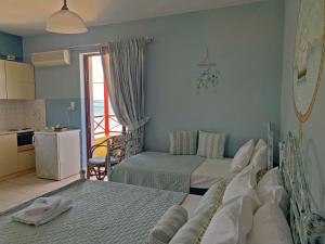 a bedroom with two beds and a kitchen with a window at Akrotiri Rooms in Agiokampos