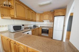 a kitchen with wooden cabinets and a white refrigerator at Apto Gerard in L'Ampolla