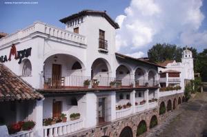 a white building with windows and balconies on a street at Posada de la Mision, Hotel Museo y Jardin in Taxco de Alarcón