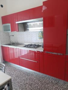 una cucina con armadi rossi e piano cottura di Interno2 a Diano Marina