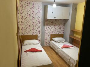 Habitación pequeña con 2 camas y papel pintado de color rosa en Apartment Karavelov, en Varna