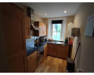 a small kitchen with wooden cabinets and a window at Central Edinburgh Private Garden with parking in Edinburgh