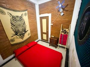 a room with a red couch and an owl on the wall at Omah Tukangan Homestay in Yogyakarta