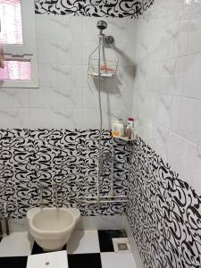 La salle de bains est pourvue d'un mur noir et blanc à motifs. dans l'établissement GRAND APPARTEMENT Au calme, ORAN -ALGERIE, à Oran