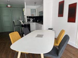 - une table et des chaises blanches dans la cuisine dans l'établissement Appartement Le Temple Auxerre Centre Ville, à Auxerre