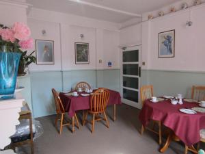 uma sala de jantar com duas mesas com toalha de mesa roxa em Athollbank Guest House em Dundee