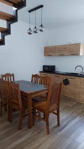 uma cozinha com uma mesa de madeira e cadeiras de madeira em Domek nad potokiem em Stronie Śląskie