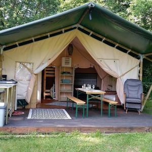 a tent with a table and chairs in it at La lodge du Refuge in Valigny