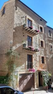 un gran edificio de piedra con balcones y flores. en "Locanda Susuiusu" keyless entry en Enna