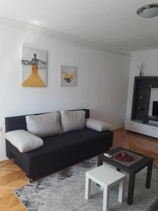 uma sala de estar com um sofá preto e uma mesa em Apartman Nataša BL em Banja Luka