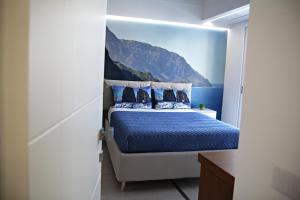 1 dormitorio con 1 cama con sábanas y almohadas azules en Room Capri en SantʼAntonio Abate