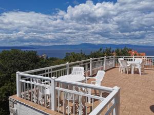 d'un balcon avec des chaises blanches, une table et une vue sur l'océan. dans l'établissement Apartments and Rooms Njivice, à Njivice