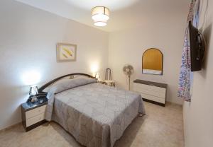 1 dormitorio con cama, mesa y ventilador en casa familiar La Lunara, en Cáceres