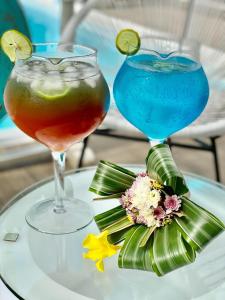 Rodrigues Island的住宿－Au Temps D'antan- Ile Rodrigues，桌上的两杯鸡尾酒,配上鲜花和饮料