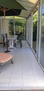 an empty porch with a table and an umbrella at Maison provençale au calme dans son grand jardin in Salles-d'Aude