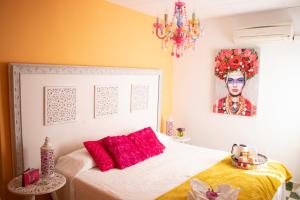 Un dormitorio con una cama con almohadas rojas y una pintura en Hostal La Fonda Grupo Terra de Mar, alojamientos con encanto, en Benissa