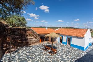 Cette maison dispose d'une terrasse avec des chaises et un parasol. dans l'établissement Varandas de Monsaraz, à Monsaraz