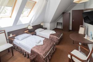 um quarto de hotel com duas camas e uma mesa em Hotel Pod Filarami em Czeladź