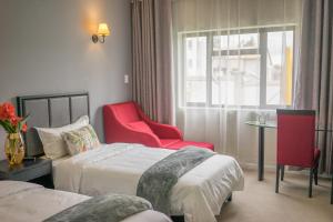 um quarto de hotel com duas camas e uma cadeira vermelha em Atlantic Pearl Guest House Broadacres em Sandton
