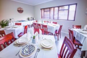 a dining room with white tables and red chairs at Atlantic Pearl Guest House Broadacres in Sandton