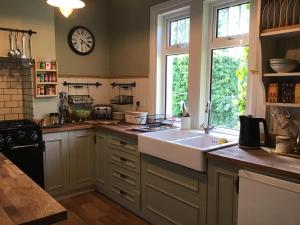 een keuken met een wastafel en een klok aan de muur bij The Blue Cottage in Antrim