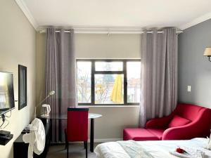 Sandton的住宿－Atlantic Pearl Guest House Broadacres，一间设有床铺、红色椅子和窗户的房间