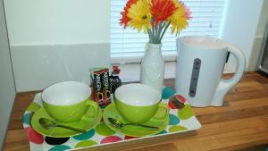 a tray with two cups and a vase with flowers at The Jorvik Mini studio with Parking in York