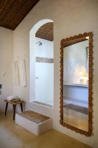 a bathroom with a mirror and a bench and a sink at Hotel Calá & Divino in Praia do Espelho